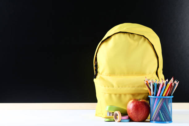 istock Yellow backpack with school supplies on black background 1036609408