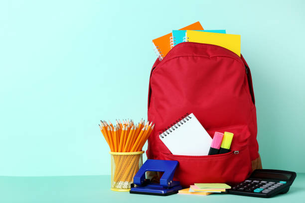 istock Red backpack with school supplies on mint background 1036609766