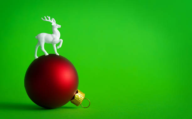 istock White reindeer on red Christmas bauble decoration on green background. 1036611400