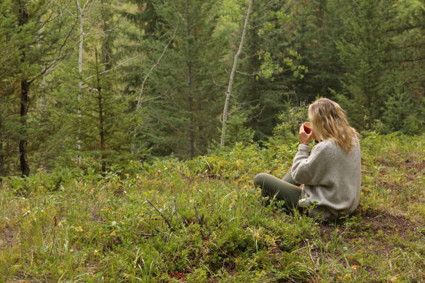 istock Woman drinks morning coffee, while sitting in forest meadow 1036611490