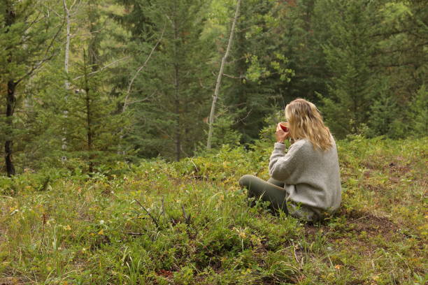 istock Woman drinks morning coffee, while sitting in forest meadow 1036611518
