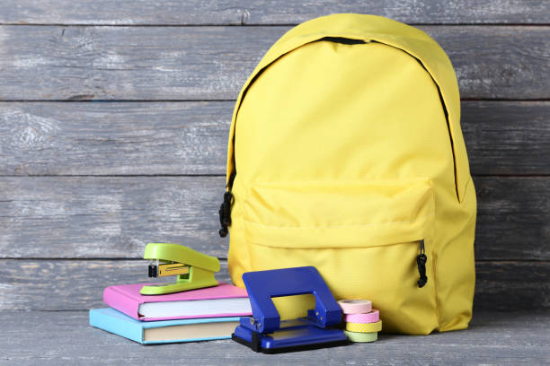 istock Yellow backpack with school supplies on wooden background 1036615324