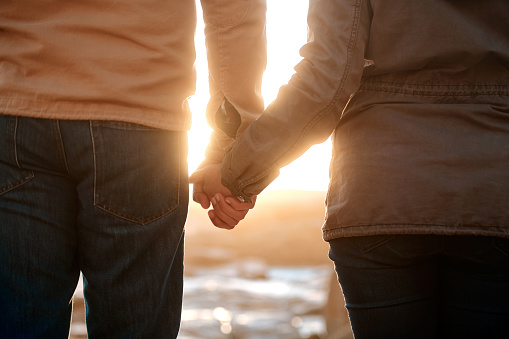 Rearview shot of an unrecognizable senior couple holding hands while standing on the beach