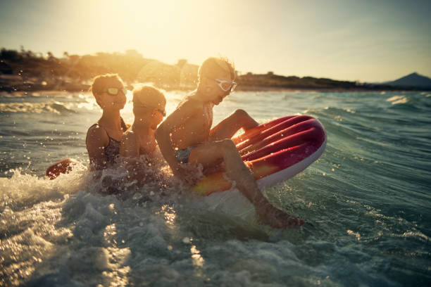 istock Three kids playing in sea on sunset 1036623050