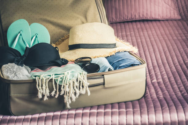 istock Open suitcase with female clothes for beach vacation. 1036625584