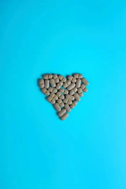 Photo of Natural Supplements in the form of a heart on a light background. The concept of alternative medicine