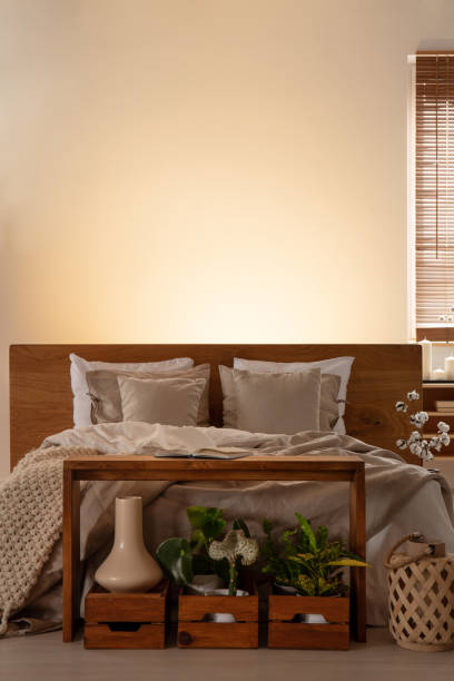 istock Empty wall in a cozy bedroom interior with a bed and plants in boxes in front. Real photo. Place your painting 1036636530