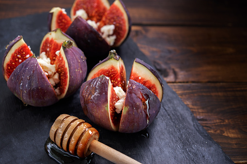Three figs stuffed with cheese and honey on slate plate