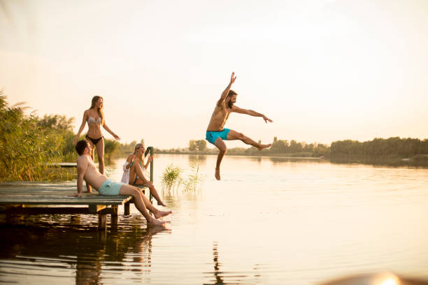 istock Group of young people having fun on pier at the lake 1036656714