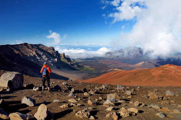 Tourist hiking in Haleakala volcano crater on the Sliding Sands trail. Beautiful view of the crater floor and the cinder cones below. Maui, Hawaii stock photo
