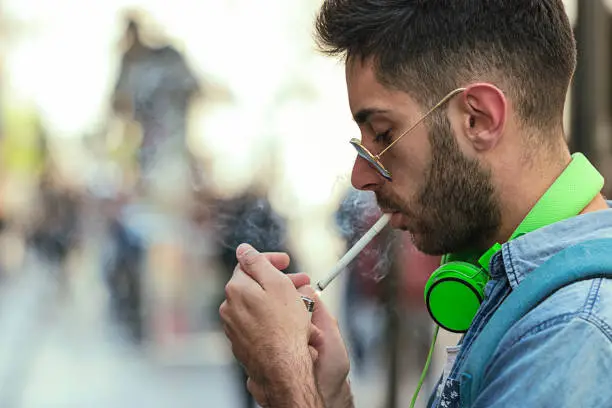 Photo of Man is lighting up a cigarette outdoors.