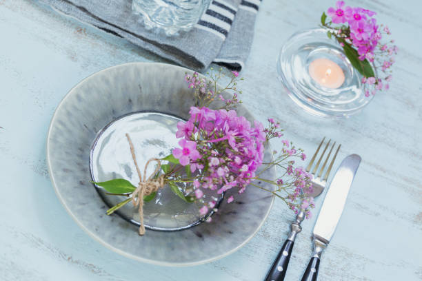 istock Rustic table setting with pink flowers and candle on light wooden table. 1036665134