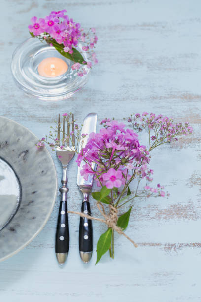 istock Rustic table setting with pink flowers and candle on light wooden table. 1036665166