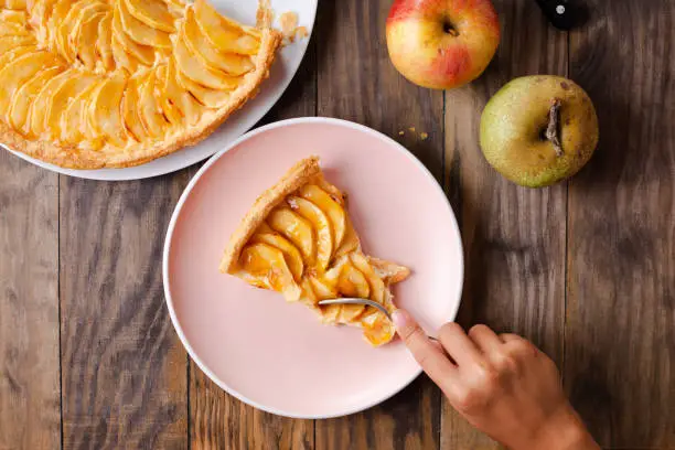 Photo of Child hand eating a portion of apple tart