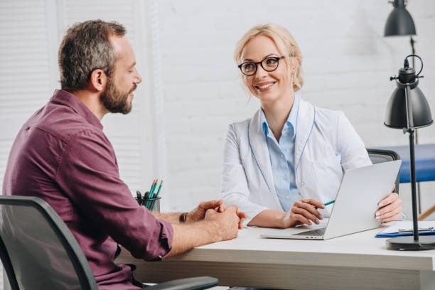 istock smiling chiropractor pointing at laptop screen during appointment with patient in hospital 1036676896