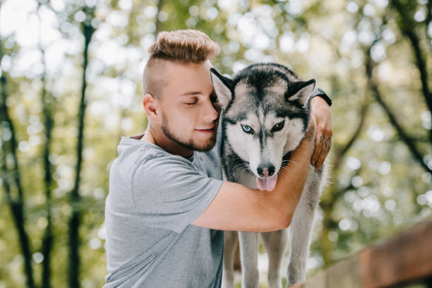 istock young man hugging husky dog in park 1036681878