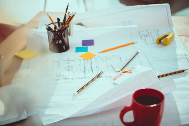 istock Close-up view of various office supplies, coffee cup and blueprints on office table 1036688780