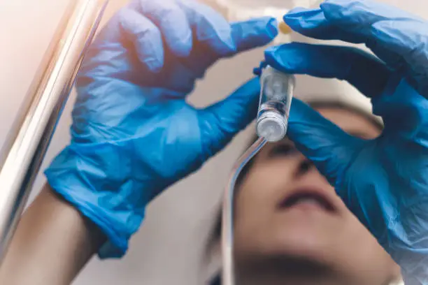 Photo of Nurse with blue gloves adjusting IV