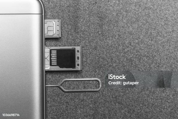 Mobile Phone And Open Slots For Nano Sim Cards Micro Sd Drive And Metal Key On Grey Background With Copy Space Black And White Photo Stock Photo - Download Image Now
