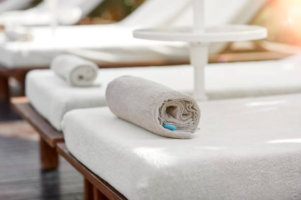 Rolled white clean towel placed on the bed beside swimming pool. Background with copy space.