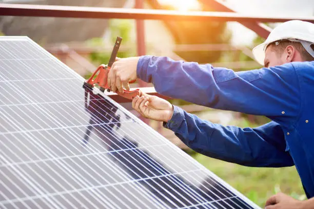 Process of connecting solar photo voltaic panel by professional technicians outdoors on bright sunny summer day. Stand-alone exterior solar panel system installation concept.
