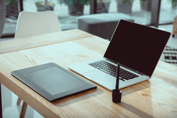 istock laptop with blank screen and graphics tablet on wooden tabletop at office 1036720308