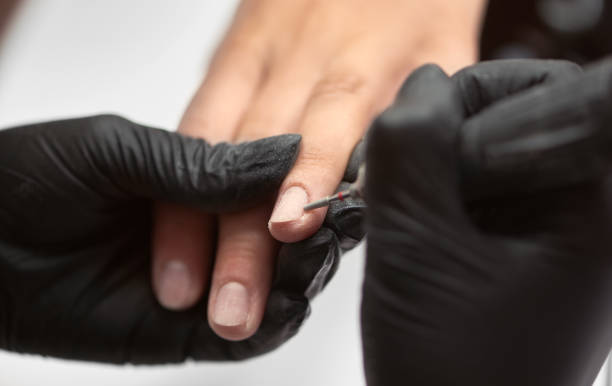 istock Close-up of professional beautician hands working with electric drill file on client fingernails. 1036731386