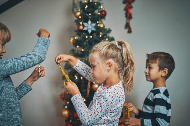 istock Cute Kids Decorating Christmas Tree with Ornaments and Christmas Lights 1036732046