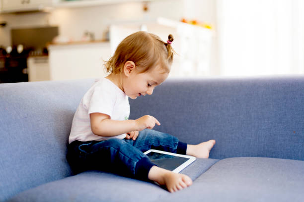 urocza dziewczyna za pomocą cyfrowego tabletu - sofa indoors childhood technology zdjęcia i obrazy z banku zdjęć