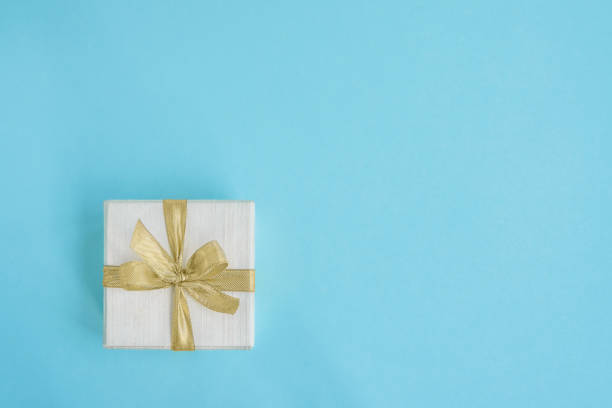 istock Gift or present box decorated with golden ribbon on light blue background. Top view, copy space. 1036747680