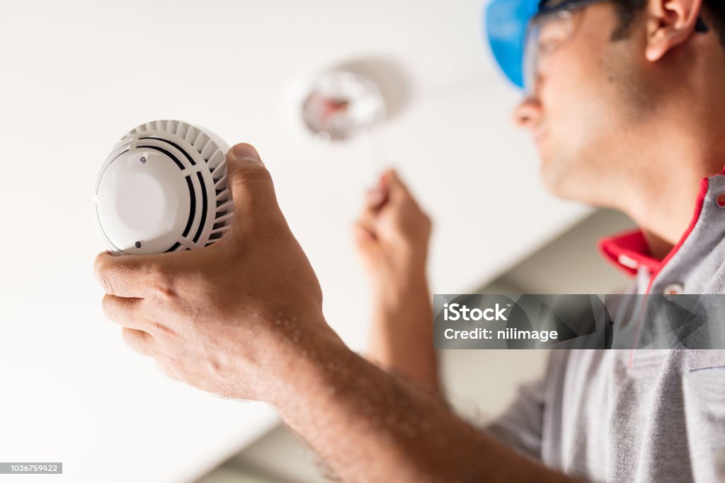Man installing smoke detector Installing smoke alarm Fire - Natural Phenomenon Stock Photo