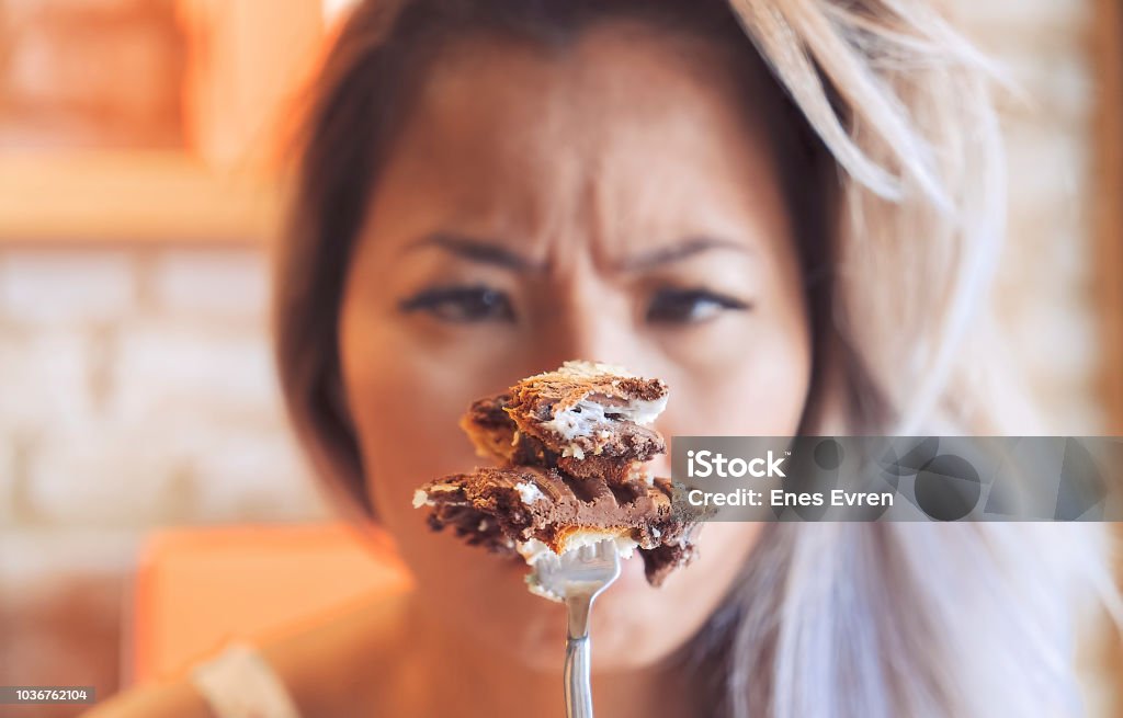 Depressed and angry woman comforting herself, eating cake Carbohydrate - Food Type Stock Photo