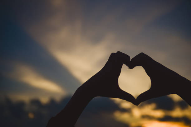 istock Love sign Heart shape hand  silhouette in sunset sky background. 1036763394