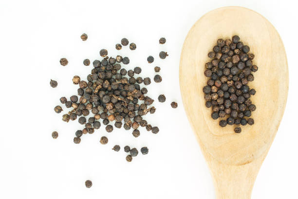 istock peppercorns in spoon heap on white background. 1036763600