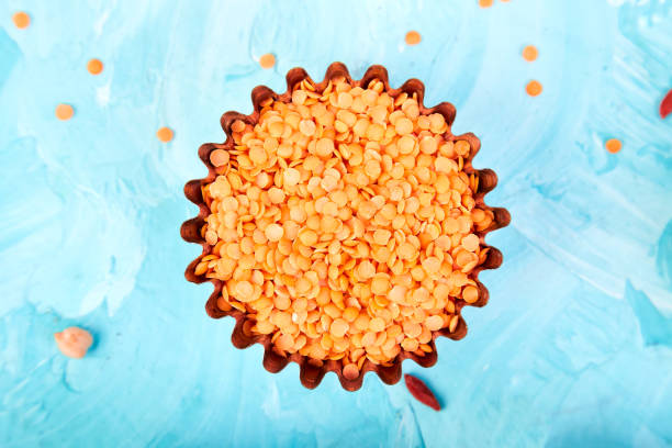 lenticchie arancioni superfoods in piccola ciotola su sfondo blu. - quinoa sesame chia flax seed foto e immagini stock