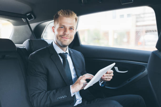 istock Executive businessman at the back of car using a digital tablet 1036774418