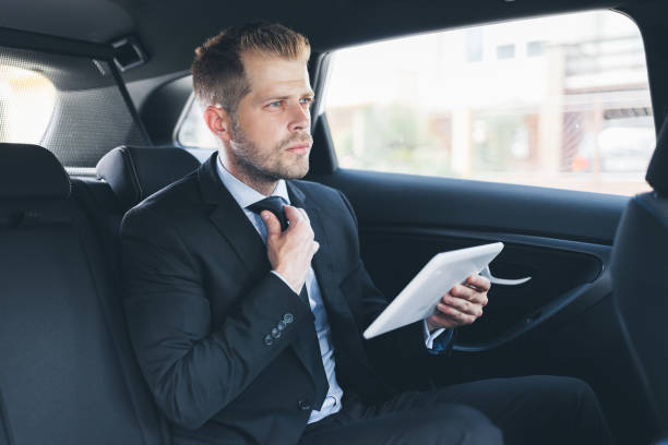 istock Executive businessman at the back of car using a digital tablet 1036774682