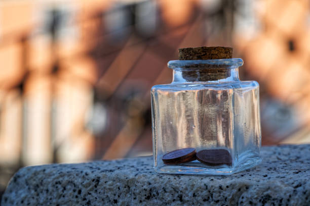 garrafa com moedas fica em um banco do parque, frasco transparente - transparent ideas lid glass - fotografias e filmes do acervo