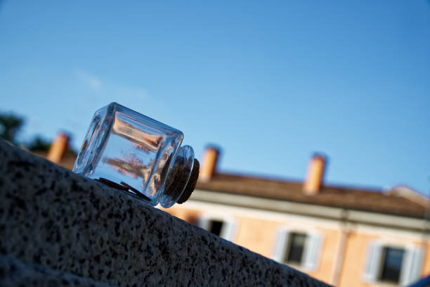 bouteille avec des pièces se trouve sur un banc de parc, bocal transparent - transparent ideas lid glass photos et images de collection