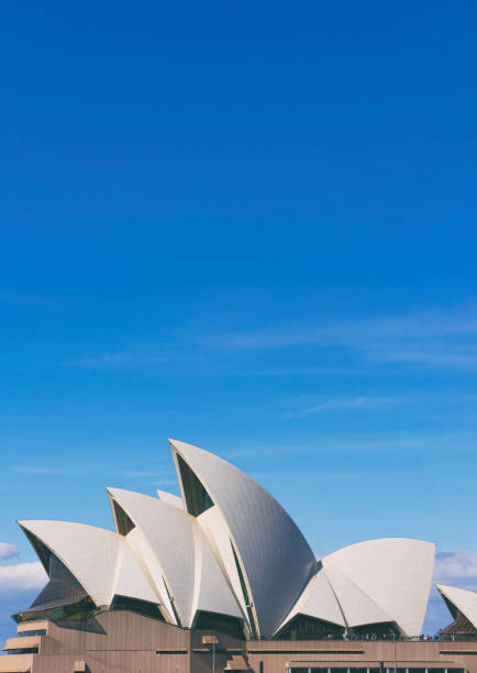 Sydney, NSW, Australia-November 8, 2015: The iconic Sydney Opera House sits next to Sydney Harbour. This image was shot at the waterfront on the grounds of the Opera House. The building features sweeping arcs that create a unique landmark for the city of Sydney.