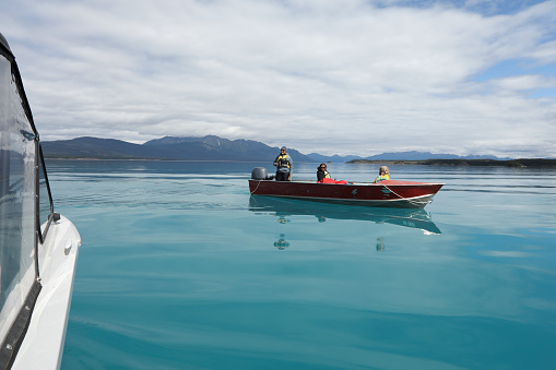 Friends fishing on a boat on Atlin Lake in Northern BC, Canada