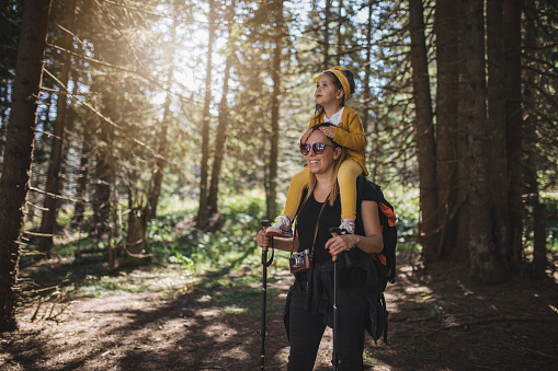 Cute and lovely family of mother and daughter, hiking a pine forest together, living a healthy lifestyle.