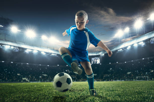 istock Young boy with soccer ball doing flying kick at stadium 1036809288