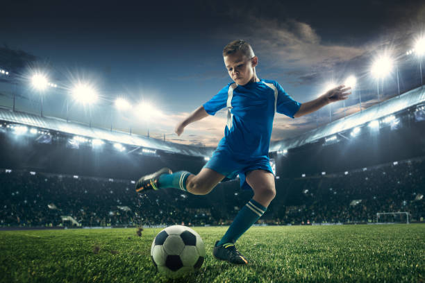 istock Young boy with soccer ball doing flying kick at stadium 1036809292