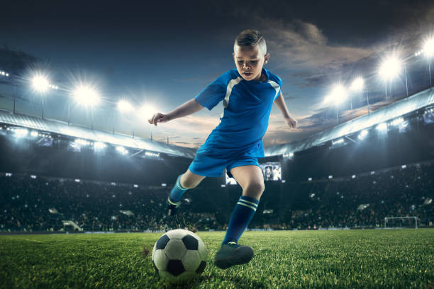 istock Young boy with soccer ball doing flying kick at stadium 1036809300