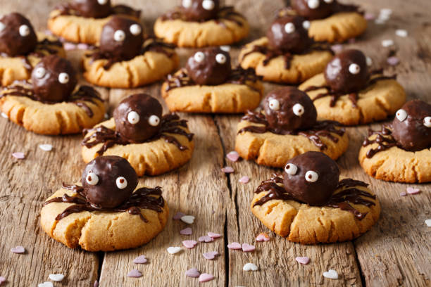 Halloween dessert: shortbread cookies with chocolate spiders close-up. horizontal background Halloween dessert: shortbread cookies with chocolate spiders close-up on a wooden table. horizontal background eye candy stock pictures, royalty-free photos & images