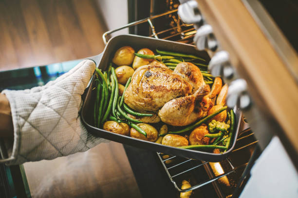 Cook taking ready chicken from the oven Cook taking ready fried baked chicken with vegetables from the oven. Healthy cooking concept. poultry stock pictures, royalty-free photos & images