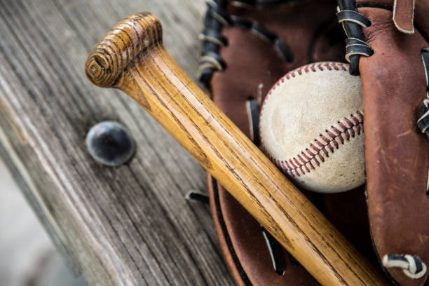 野球のシーズンはここにです。 バット、グローブ、ダッグアウトのベンチ上のボール。 - dugout baseball bench bat ストックフォトと画像