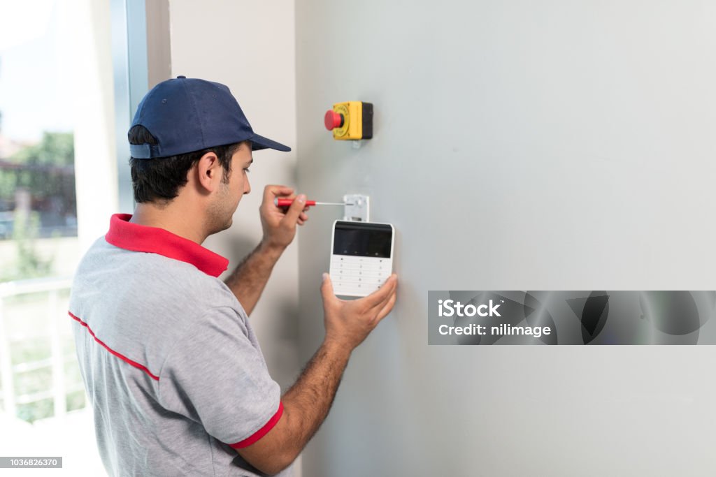 Man installing security alarm system Technician set up keypad of security alarm system Burglar Alarm Stock Photo