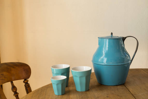 istock Blue jar with three blue cups on a wooden table with a chair indoors 1036832392